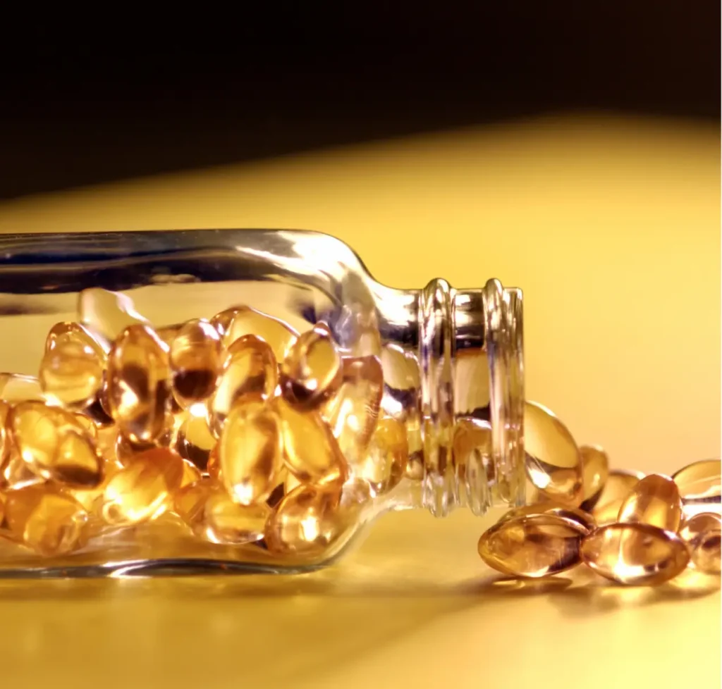 Frascos de suplemento de Vitamina E junto a alimentos ricos en vitaminas como almendras y espinacas.